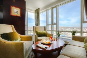 a living room with a table and chairs and a large window at Best Western Premier Tuushin Hotel in Ulaanbaatar
