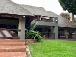 a house with a thatch roof and a grass yard at Monchique Boutique Guest House in Muldersdrift