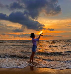 a young girl standing on the beach pointing at the sunset at Sevenseas Seaview Homestay in Port Dickson