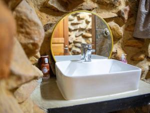 a white sink in a stone bathroom with a mirror at Mount Lake Cabins in Harrismith