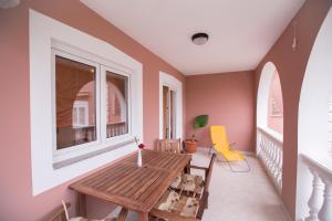 a balcony with a wooden table and a window at Apartments Dunja Piric in Lopar
