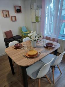 uma mesa de jantar com cadeiras, pratos e flores em Duplex centre ville em Ernée