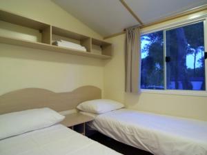 ビオグラード・ナ・モルにあるComfortable chalet with two bathrooms at 31 km from Zadarのベッド2台と窓が備わる小さな客室です。