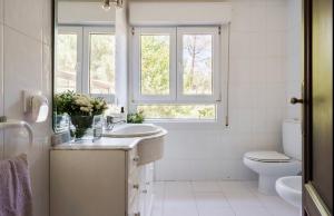 Un baño blanco con lavabo e inodoro. en Finca LaGloria, en Guadarrama 37 fotos más
