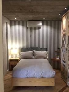 1 dormitorio con 1 cama con pared a rayas en Canela Fina - Adults Only, en San Miguel de Allende