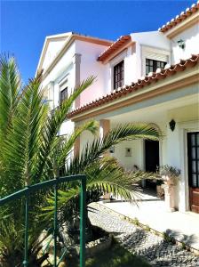 una casa blanca con una palmera delante en Baleal - Large villa near beach up to 12 PAX+2 CH, en Peniche