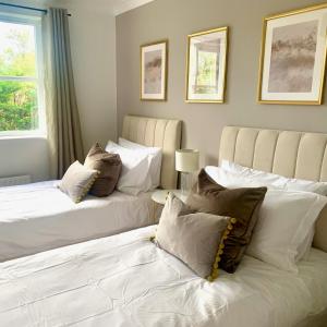 - 2 lits dans une chambre avec des oreillers blancs dans l'établissement Bright modern flat in central Twickenham, à Twickenham