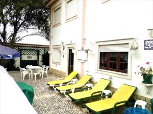 Una fila de sillas y mesas amarillas afuera de un edificio en Baleal - Large villa near beach up to 12 PAX+2 CH, en Peniche