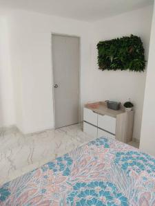 a bedroom with a bed and a table with a plant on the wall at Hermoso e iluminado apartamento. in Itagüí