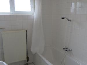 a white bathroom with a tub and a window at Detached bungalow with dishwasher at the water in Medemblik