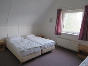 a bedroom with a bed and a window at Detached bungalow with dishwasher at the water in Medemblik