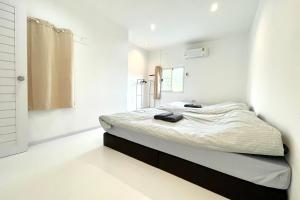 - une chambre blanche avec un lit et un miroir dans l'établissement เดอะ ชะอม The ChaOm, à Ban Cha-om