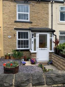 a house with a white door and some flowers at Quaint 1 bedroom cottage in Pudsey, Leeds in Pudsey