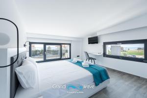 a white bedroom with a bed and a tv at Grand Wave Luxury Suites in Flogita