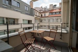 2 chaises et une table sur un balcon avec des bâtiments dans l'établissement Krakovska CR Apartments, à Prague