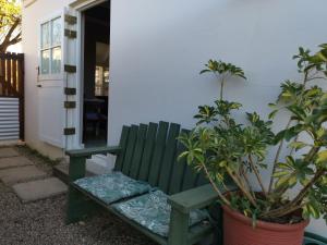 a green bench sitting outside of a house with plants at 30 Oak Street in Greyton