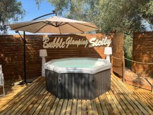 a hot tub sitting under an umbrella on a deck at Bubble Glamping Sicily in Catania