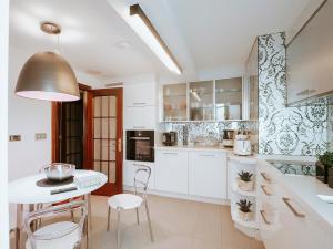 a kitchen with white cabinets and a table and chairs at Lujoso apartamento Centro a 3 minutos de la playa in A Coruña