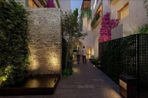 two people walking down a walkway in a building at Le Cottage San Miguel de Allende, Modern Luxury in Centro with Pool & Jacuzzi in San Miguel de Allende