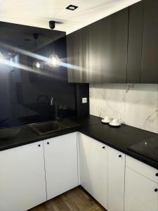 a kitchen with white cabinets and a black counter top at Apartament 11 Listopada in Ostrołęka