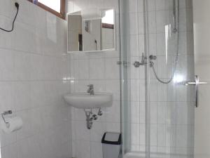 a white bathroom with a sink and a shower at Nice house with sauna and steam bath in a forest in Sellerich