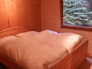 Nice house with sauna and steam bath in a forest في Sellerich: سرير في غرفة خشبية مع نافذة