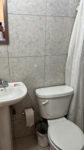 a bathroom with a white toilet and a sink at Hotel Regina “El Llano” in Cosalá