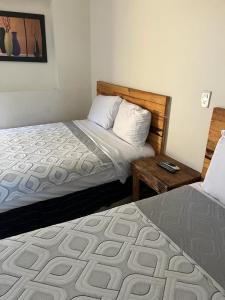 a bedroom with two beds and a wooden headboard at Hotel Regina “El Llano” in Cosalá