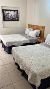Tres camas sentadas una al lado de la otra en una habitación en Hotel Regina “El Llano”, en Cosalá