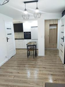 a room with a table and a kitchen with white cabinets at Apartament 11 Listopada in Ostrołęka