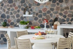 a white table with a bowl of fruit and wine glasses at Ode Villa in Oia