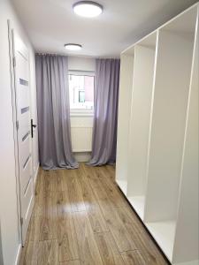 Pokój z białymi szafami i drewnianą podłogą w obiekcie Apartament 11 Listopada w mieście Ostrołęka
