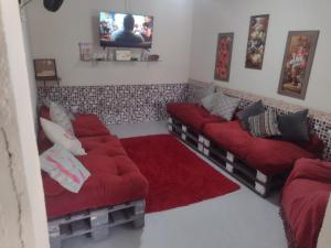 a living room with two red couches and a tv at Cabo frio house in Cabo Frio