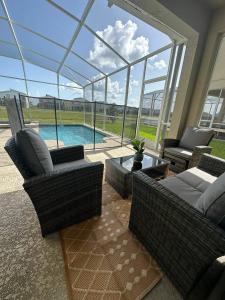 a living room with wicker furniture and a swimming pool at 5bedroom Amazing home close to Disney Resort 8934 in Kissimmee