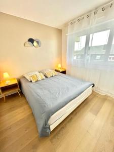 een slaapkamer met een groot bed en een raam bij LE COSY avec piscine, balcon et parking in Trouville-sur-Mer