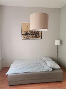 a white bedroom with a bed with a lamp at EVA Apartment in Novi Sad