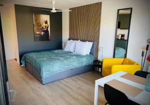 um quarto de hotel com uma cama e uma cadeira amarela em Flamingo Studio's Zeeland em Schoondijke