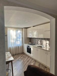 a kitchen with white cabinets and a stove top oven at Guest house Zuzumbo in Tʼelavi