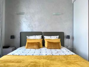 1 dormitorio con 1 cama con sábanas y almohadas amarillas en Elegant studio proche Palais des Festivals, en Cannes