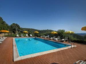 una piscina con sedie e ombrelloni di Cozy Farmhouse in Paciano with Private Pool a Paciano