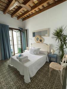 Un dormitorio con una gran cama blanca y una silla. en Doña Lola Rooms, en Conil de la Frontera