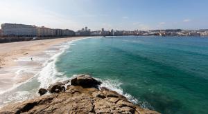 a view of a beach with a city in the background at Lujoso apartamento Centro a 3 minutos de la playa in A Coruña