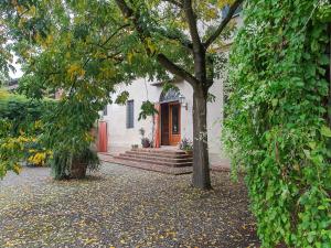 a white house with a red door and a tree at Quaint Mansion in Stagno Lombardo with Garden in Stagno Lombardo