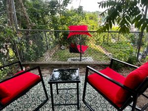 balkon z czerwonymi krzesłami, stołem i ogrodzeniem w obiekcie 8-A Diamond in Yonkers, NY w mieście Yonkers