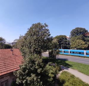 een blauwe trein die door een straat rijdt met een boom bij BRIGHT CITY CENTER Apartment - FlexibleCheckins in Zagreb