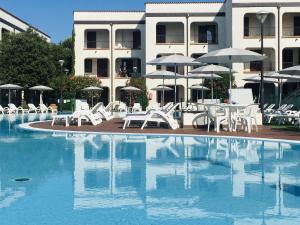 a pool with white chairs and tables and umbrellas at Comfy apartment with AC located at the beach in Lido di Spina