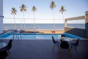 eine Terrasse mit einem Tisch, Stühlen und Meerblick in der Unterkunft Cowork Lab Suites in Maputo