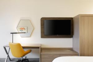 a bedroom with a desk and a tv and a yellow chair at Holiday Inn Express Toledo North, an IHG Hotel in Toledo