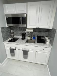 a kitchen with white cabinets and a sink and a microwave at Villa Sosa in Fort Myers