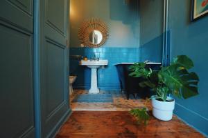 ein blaues Badezimmer mit einem Waschbecken, einer Badewanne und einer Pflanze in der Unterkunft Estacart - Grenoble Centre in Grenoble